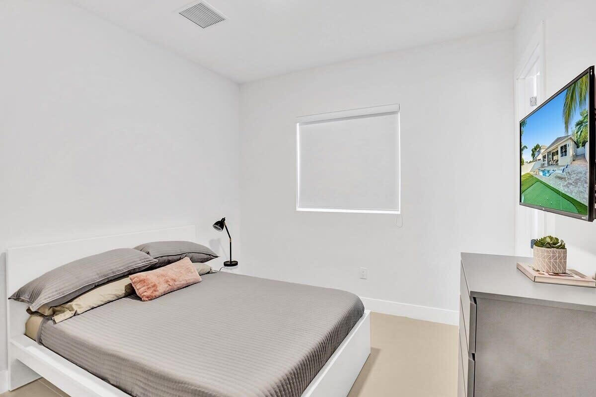 Un dormitorio con una cama, un escritorio, una silla, un televisor y una ventana.