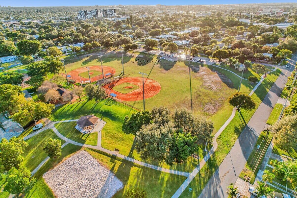 An aerial view of a park with sports fields, pathways, and surrounding residential areas.