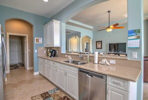 A modern kitchen with a dishwasher, double sink, and a ceiling fan.