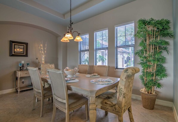 A dining area with a wooden table, chairs, and a hanging light fixture.