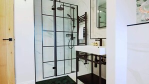 A bathroom with a glass shower enclosure, a white sink, and a mirror above the sink.
