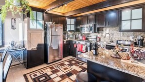 A modern kitchen with dark cabinetry, stainless steel appliances, and a patterned floor. - Serene View Chalet | Hot Tub - King Beds Mtn Views (Big Bear Lake)