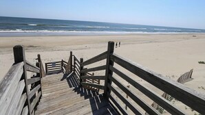 Una passerella di legno che conduce a una spiaggia sabbiosa, con l'oceano sullo sfondo.