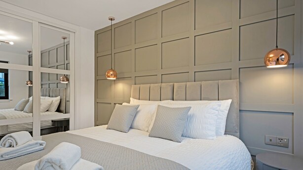 Una habitación de hotel moderna con una cama grande, un armario empotrado y una mesa redonda.