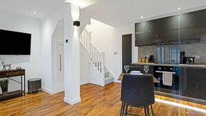 Una cocina moderna con armarios oscuros, horno integrado y comedor con mesa y sillas.