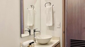 Une salle de bain moderne avec un grand miroir, un lavabo blanc et des toilettes.
