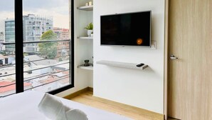 Une chambre d’hôtel moderne dotée d’une grande fenêtre, d’un téléviseur à écran plat fixé au mur et d’une porte en bois.