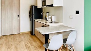Une cuisine compacte dotée d’un four à micro-ondes encastré, d’un évier et d’un plan de travail.