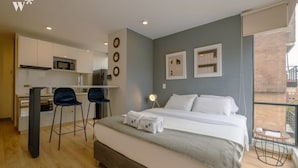 Een moderne hotelkamer met een bed, een bureau en een kitchenette.