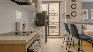 Een moderne keuken met een centraal eiland, roestvrijstalen apparatuur en uitzicht naar buiten.