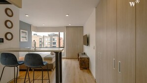 Een moderne keuken met een centraal eiland, twee barkrukken en een stadszicht door grote ramen.