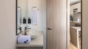 Une salle de bain moderne avec un grand miroir, un lavabo blanc et un porte-serviettes.