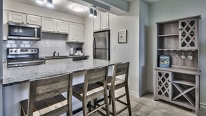 A modern kitchen with white cabinets, stainless steel appliances, a granite countertop, and wooden chairs. - Vacation and relax in a recently renovated two bedroom condo. One free beach cha (Destin)