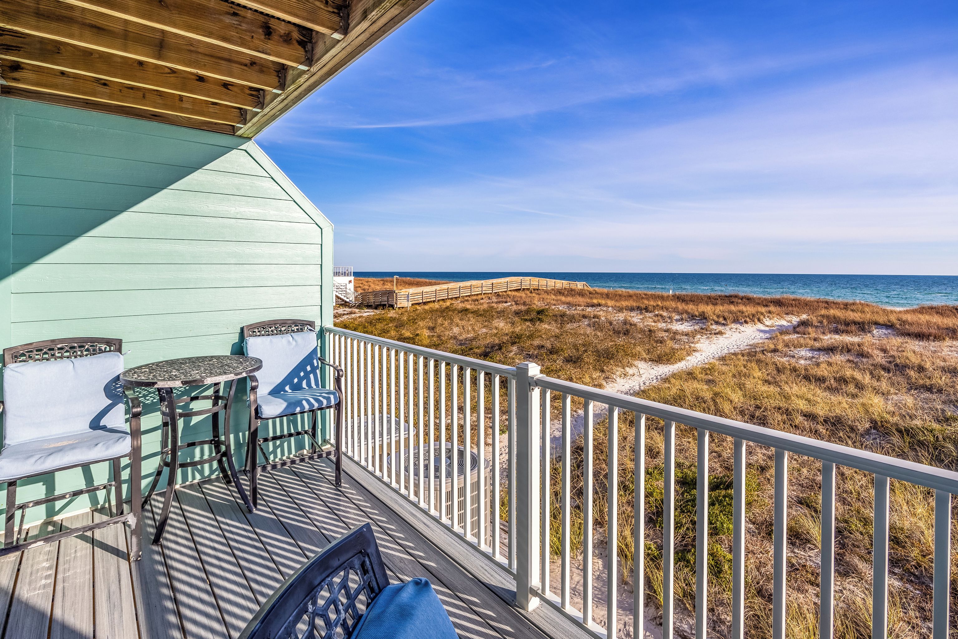 Una terraza de madera con vista a la playa y al océano.