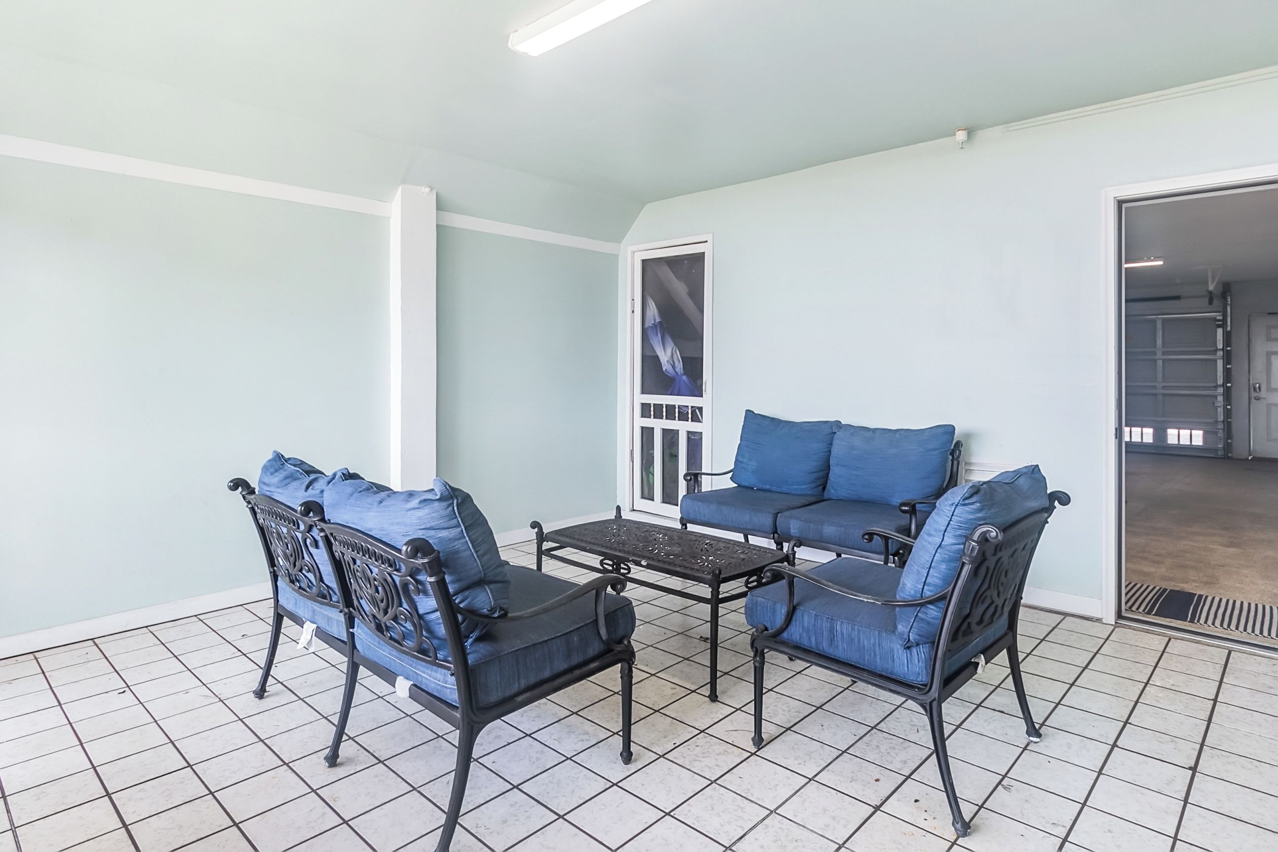 A room with a light blue wall, a black metal table, and two blue cushioned chairs.