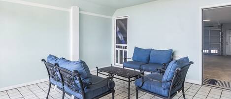A room with a light blue wall, a black metal table, and two blue cushioned chairs.