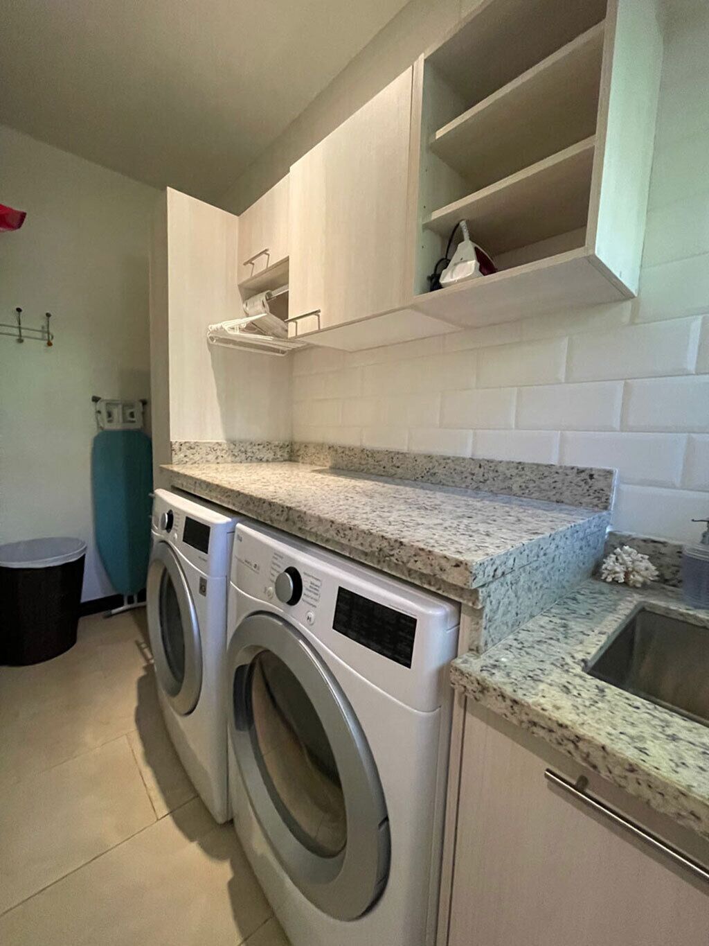 A compact kitchen with a built-in washer and dryer, white cabinets, and a granite countertop.