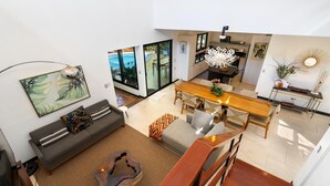 Un espacio habitable amplio con un sofá, una mesa de centro y una mesa de comedor. Una escalera conduce a un nivel superior.
