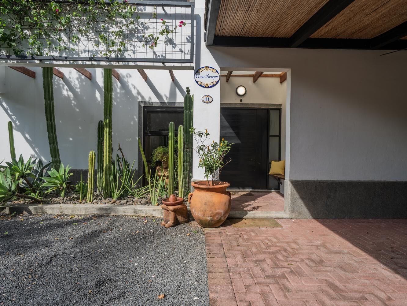 A building entrance with a cactus garden, a large terracotta pot, and a sign reading 'Casa Bosque'.