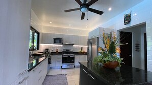 Cocina moderna con gabinetes blancos, electrodomésticos de acero inoxidable y encimera negra.