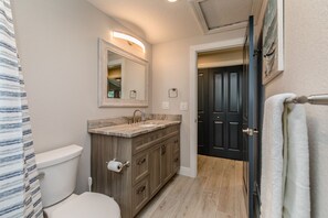 A bathroom with a toilet, vanity, sink, and mirror.