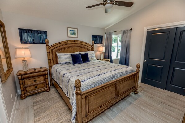 A bedroom with a wooden bed, two bedside tables, a ceiling fan, and a door.