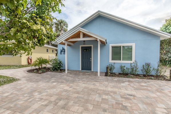 A single-story house with a blue exterior, a front porch, and a paved driveway.