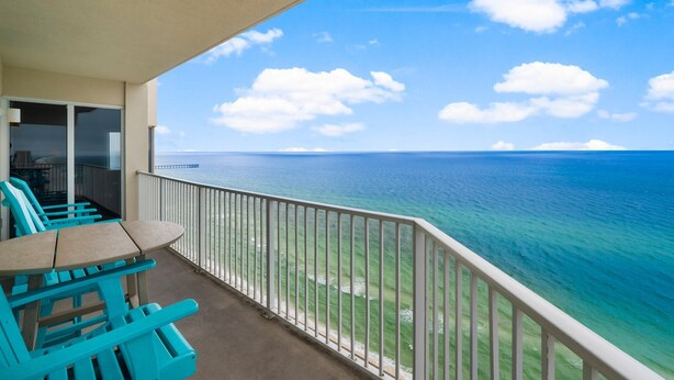 Un balcon avec vue sur l’océan, une table et des chaises bleues.