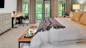 Une chambre à coucher avec un grand lit, un bureau, une chaise et une fenêtre avec des rideaux.