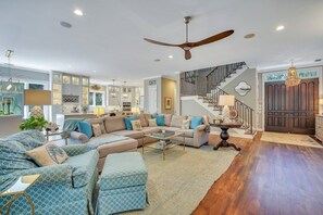 A spacious living room with a sectional sofa, a ceiling fan, and a staircase leading to an upper level.