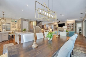 A modern kitchen with a built-in refrigerator, a dining area with a wooden table and chairs, and a staircase leading to an upper level. - PRIVATE 4th Row Beach Access, Heated Pool & Dog Friendly (Hilton Head Island)