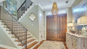 A staircase with a metal railing, a wooden door, and a chandelier. - PRIVATE Beach access, 4th Row, Heated Pool & Dog Friendly (Hilton Head Island)