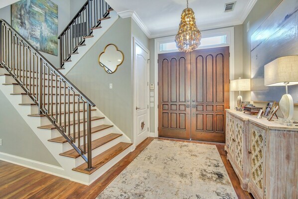 Experience the perfect blend of classic and contemporary design in this elegant space, featuring a grand staircase, ornate door, and stunning chandelier.