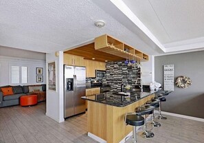 A modern kitchen with a central island, bar stools, and a built-in oven.