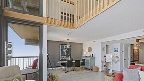 Un vaste espace de vie avec balcon, un coin repas et un canapé rouge.