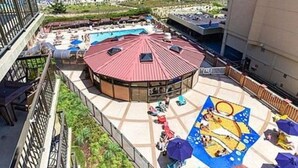 Un espace piscine aménagé sur le toit, avec une piscine circulaire, des chaises longues et des parasols.