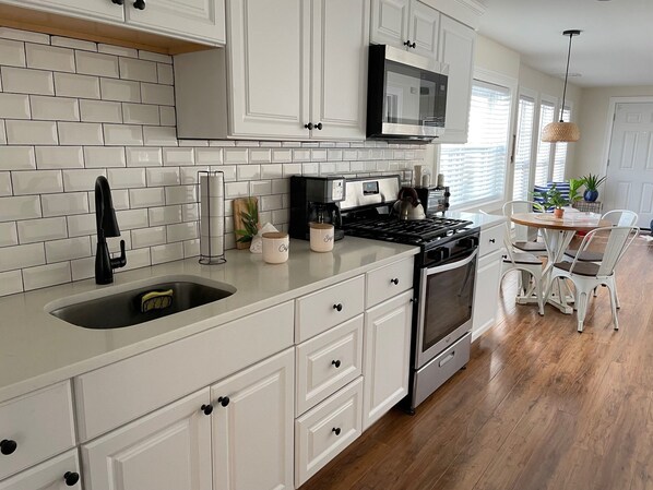 A kitchen with white cabinets, a stainless steel stove, and a microwave.