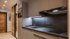 Een moderne keuken met een roestvrijstalen spoelbak, een ingebouwde oven en een afzuigkap.