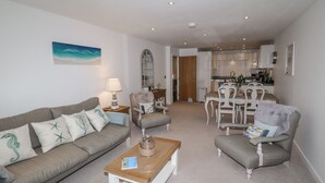 Ein Wohnzimmer mit einer Couch, Sesseln, einem Couchtisch und einem Essbereich mit Tisch und Stühlen.