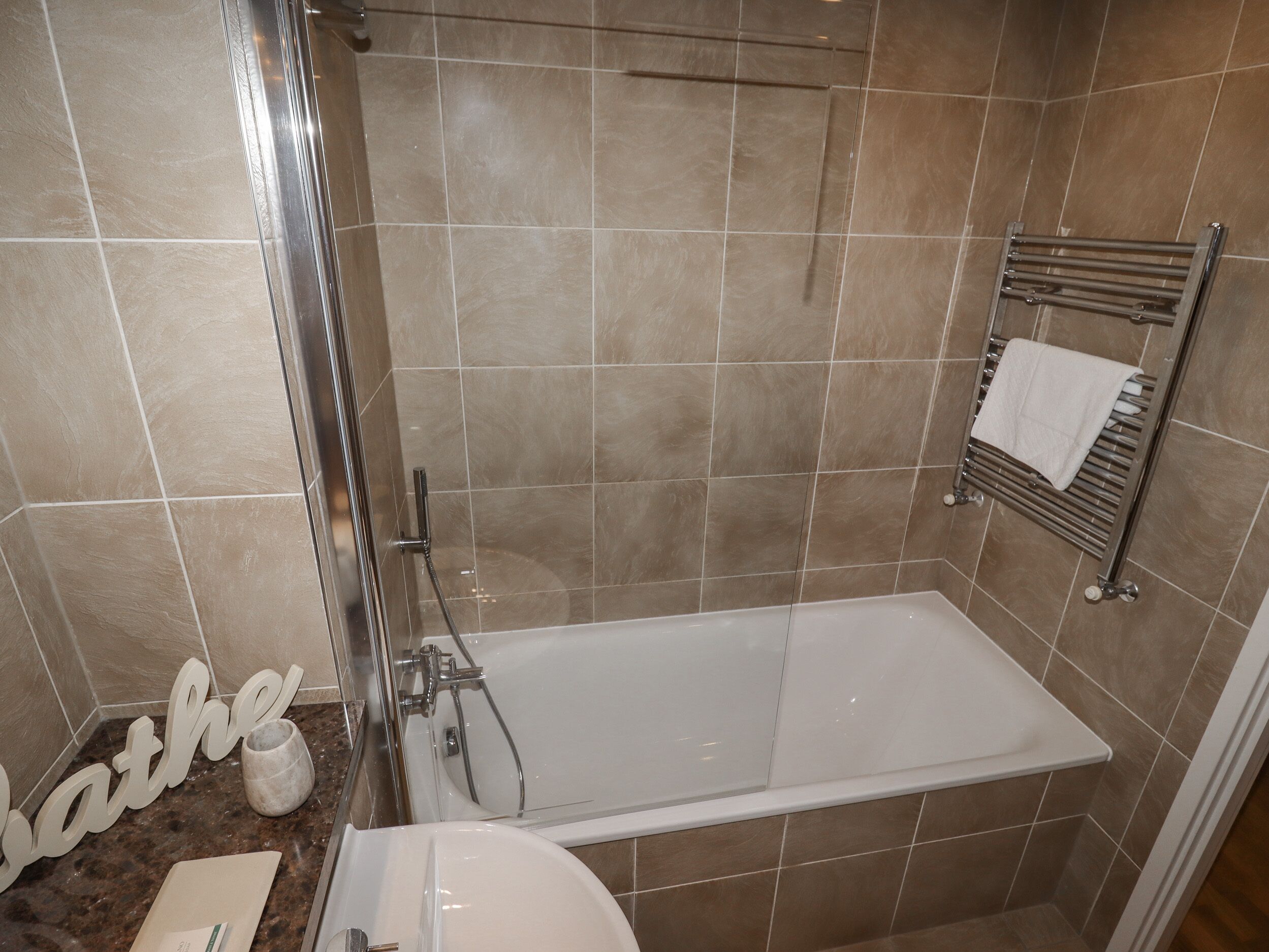 A modern bathroom with a bathtub, a shower, and a towel rack.