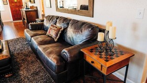 A living room with a leather sofa, a wooden side table with candles, and a chessboard.