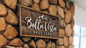 A stone fireplace with a sign reading "Est. 2021 Bellai Vista Bass Lake".