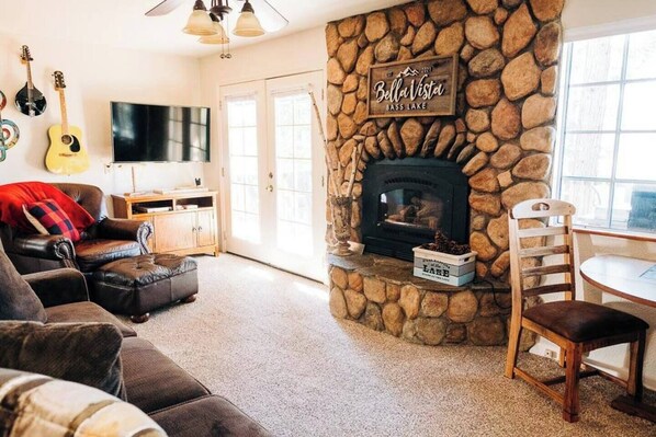 Una sala de estar acogedora con chimenea de piedra, televisión y comedor con mesa y sillas.