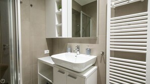 Ein modernes Badezimmer mit einem weißen Waschbecken, Spiegel und Handtuchhalter.