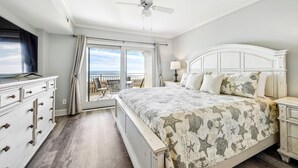 Et soveværelse med seng, kommode, natbord, loftventilator og balkon med havudsigt.