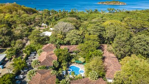 A resort with multiple bungalow-style buildings, a swimming pool, and a view of the ocean and islands. - Walk to Everything! 2BR Villa at Playa Penca - Pool, Parking + Massages on us! (Provincia de Guanacaste)