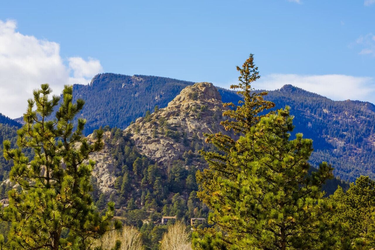 A mountain landscape with a prominent rocky peak and dense forest.