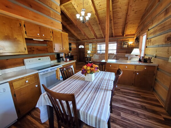 Interior de una cabaña de madera con cocina, comedor y sala de estar.