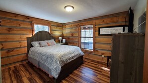 A wooden-paneled bedroom with a bed, a nightstand, a window, and a wall-mounted sign. - Villa Bonita/ Private Mountain top Cabin on 7.5 Acres w/Hot Tub (Sevierville)