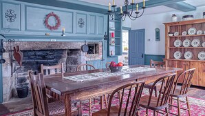 A dining room with a wooden table, chairs, a fireplace, and a chandelier. - Coastal Antique farmhouse  (North Stonington)